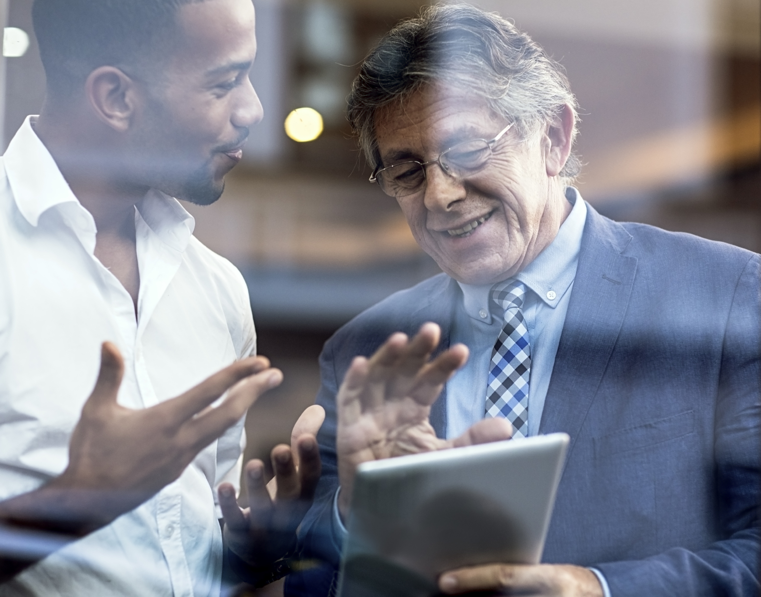Older business man with young man looking at tablet